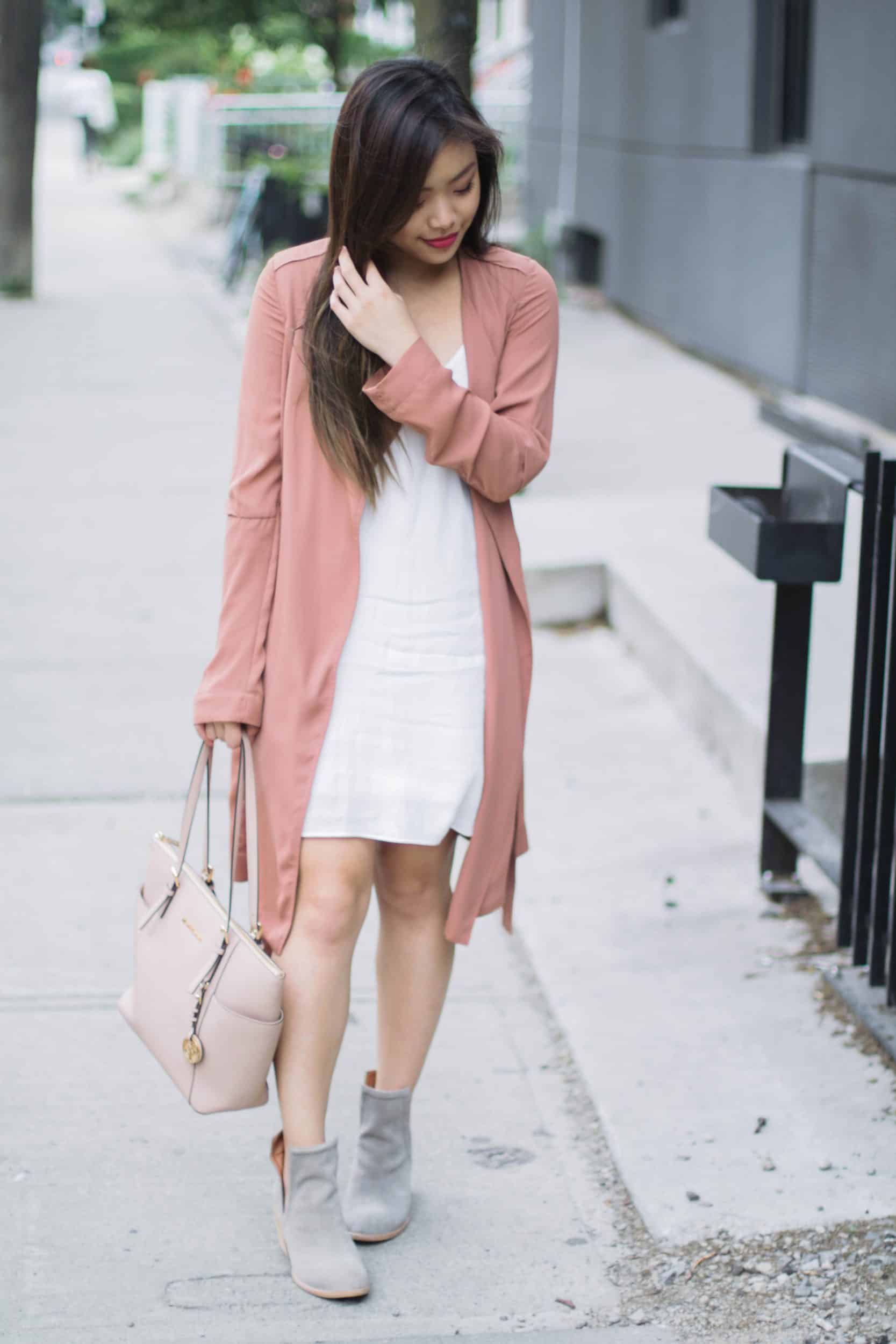 Summer outfit featuring Aritzia white slip dress, pink trench coat, Jeffrey Campbell grey suede booties, and nude Michael Kors bag