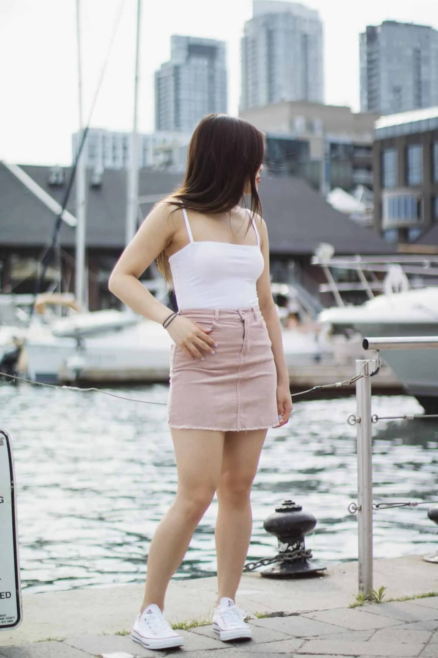 Summer outfit featuring white bodysuit, pink corduroy miniskirt, and Converse white chucks