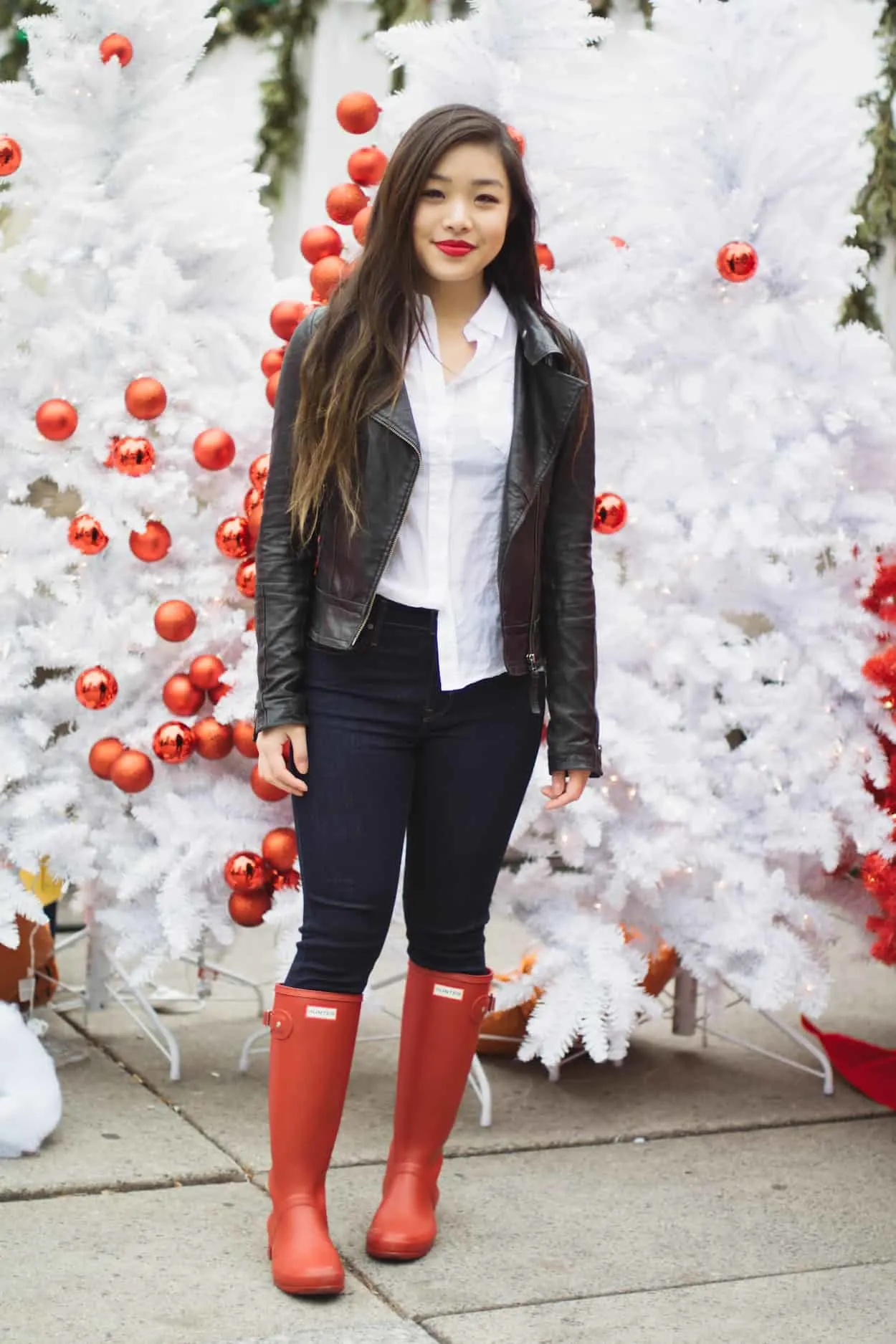 Winter outfit idea featuring a white button down, black leather jacket, Levi's dark wash denim, and red Hunter boots