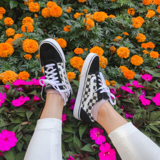 Vans Old Skool Black Sneakers with white pants over fall flowers